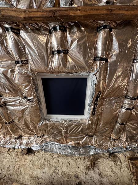 Pose de l'isolant souple de chez Actis sur le tour de la fenêtre de toit velux pour une isolation parfaite par les 2 charpentiers, artisan RGE a Albi. 